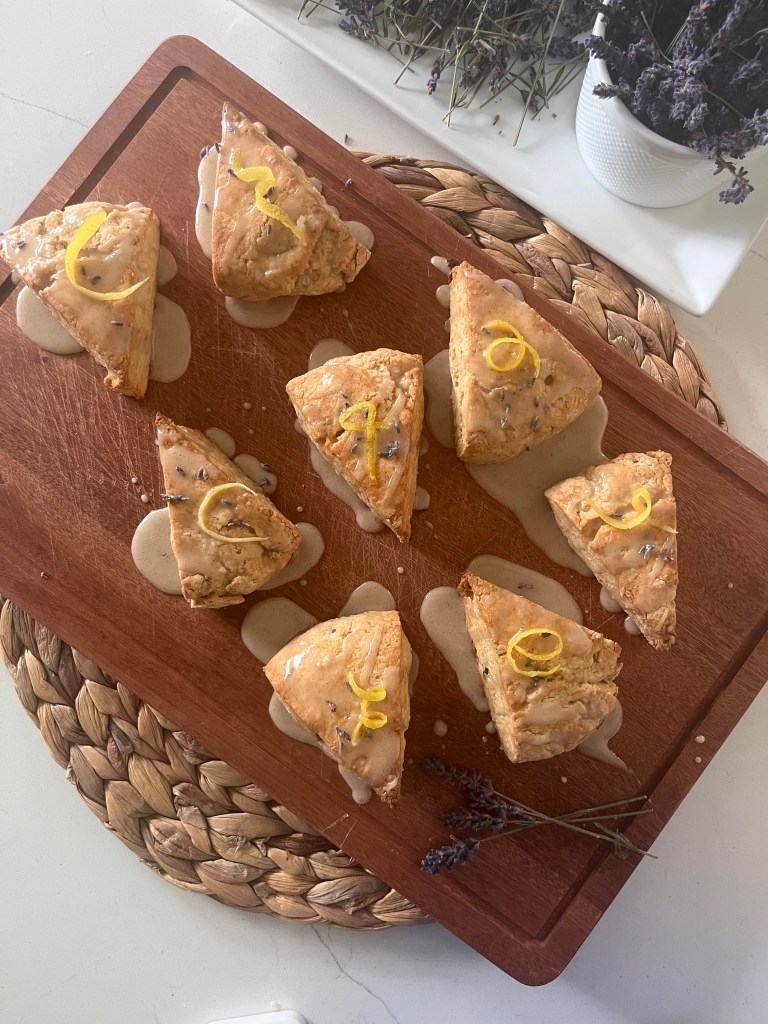 a wooden board holding lemon lavender scones on a white table

